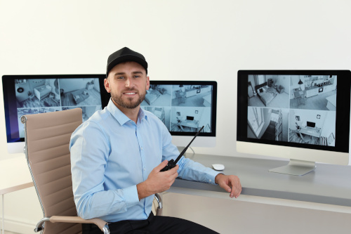 Male security guard with portable transmitter monitoring home ca Security-Mitarbeiter mit Funkgerät überwacht Monitore in einem Büro